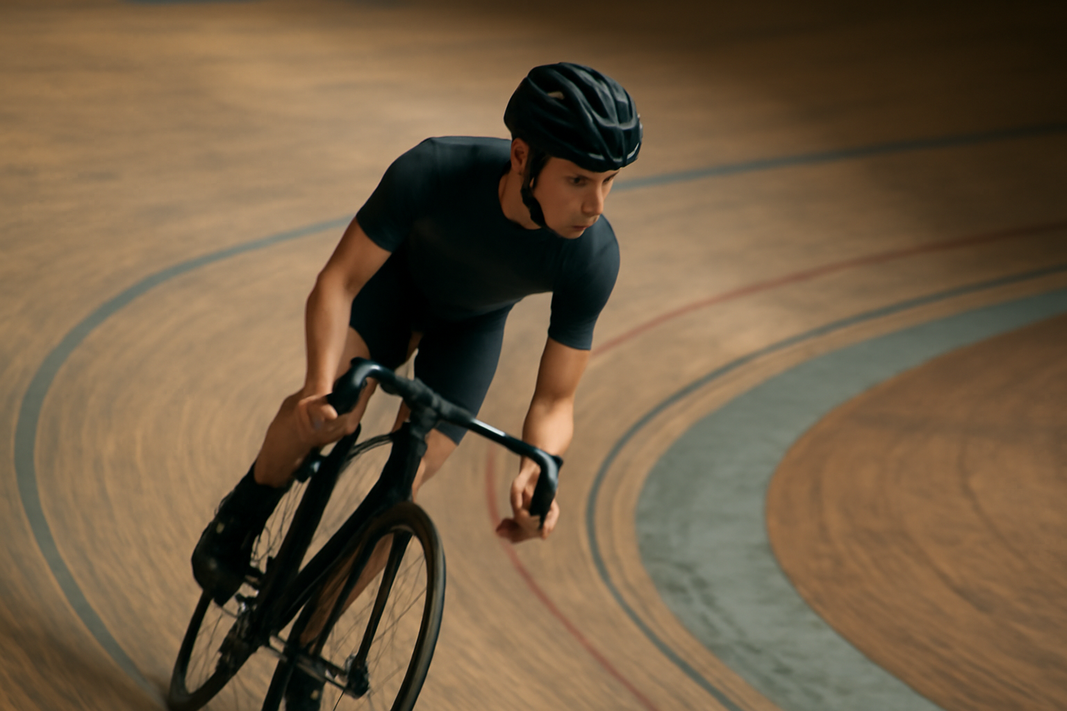 Pesepeda pemula melintasi tikungan velodrome kayu dengan sepeda trek